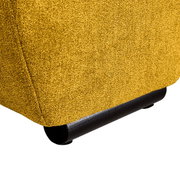 Nahaufnahme der unteren Ecke eines gelben Big-Sofas mit schwarzem Fuß, seitliche Perspektive.