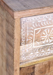 Detailansicht eines Holzmöbels mit geschnitztem Blumenmuster auf der Vorderseite.