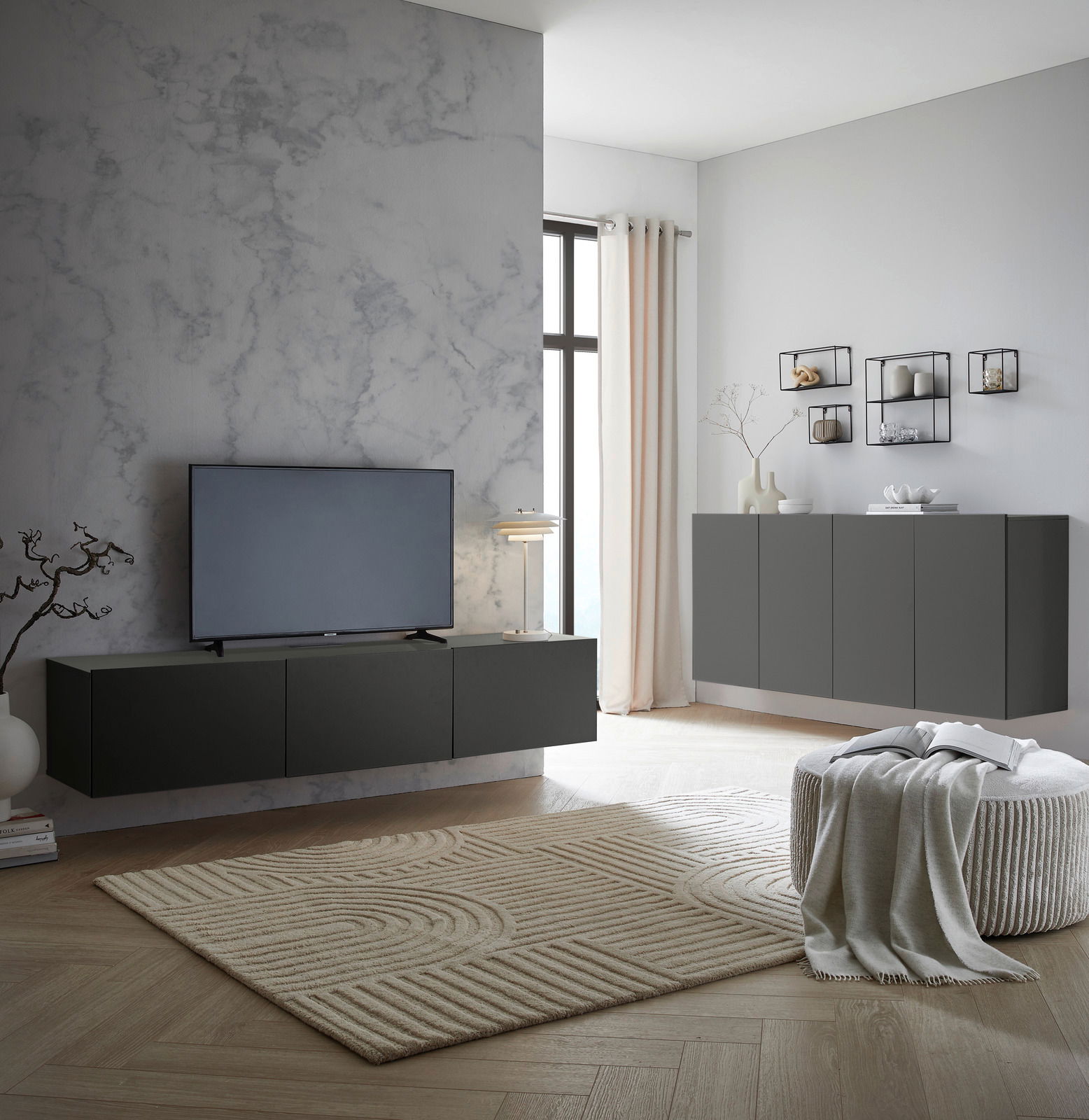 Modernes Wohnzimmer mit einem schwarzen TV-Hängelowboard an einer grauen Wand, seitliche Perspektive.