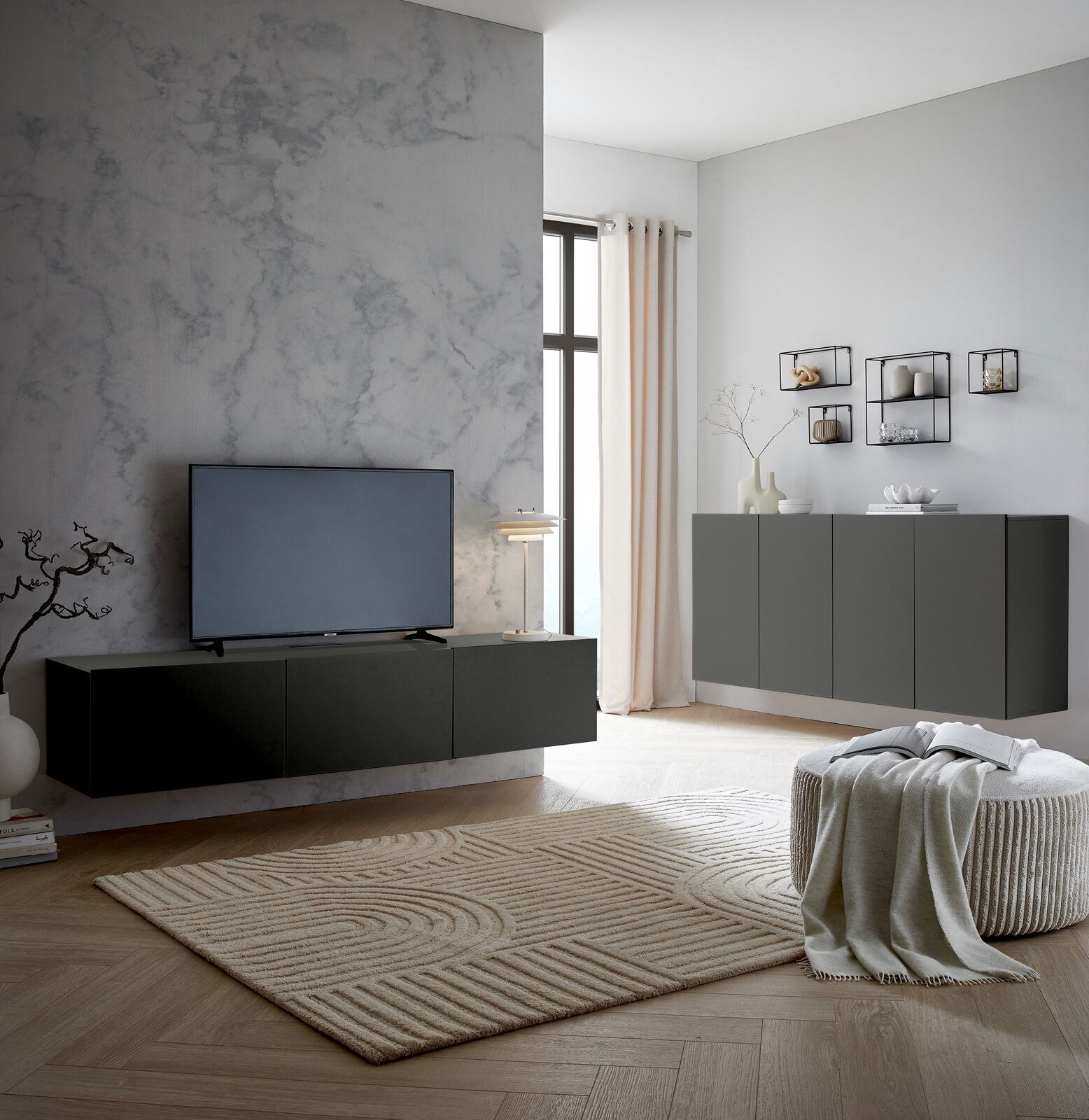 Modernes Wohnzimmer mit einem schwarzen TV-Hängelowboard an einer grauen Wand, seitliche Perspektive.