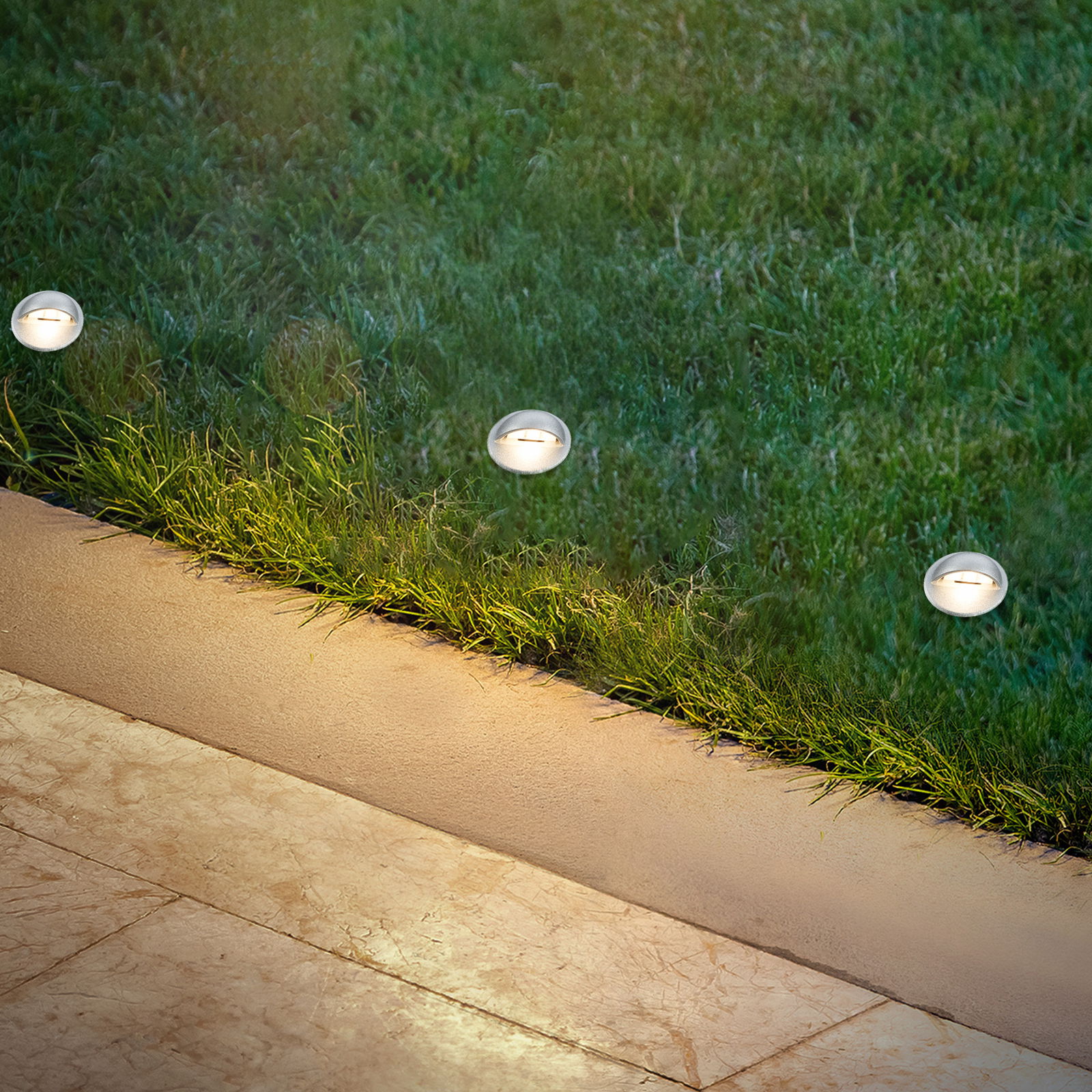 Briloner Einbaulicht-Starter-Set 3tlg. GARTENSYSTEM Einbaulicht-Starter-Set mit drei runden Leuchten, eingebaut in einen Rasen neben einem gepflasterten Weg, aus der Vogelperspektive betrachtet.