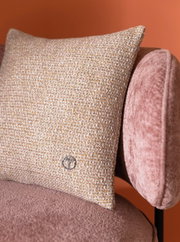 Sierkussenhoes met een beige-gouden weefpatroon op een roze fauteuil, zijaanzicht