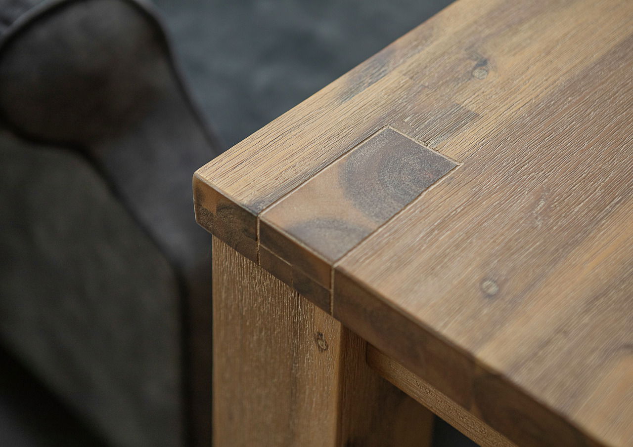 Nahaufnahme eines Esstisches aus Holz mit sichtbarer Maserung und stabiler Eckverbindung, Perspektive von oben.