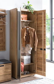 Geöffneter Garderobenschrank aus Holz mit Spiegel an der Tür, zeigt Innenraum mit Kleiderstange, Jacke, Hutablage, Schachtel und Schuhen. Perspektive von vorne.