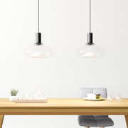 Twee moderne hanglampen met een transparante glazen kap boven een eettafel, zijaanzicht