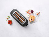 Toaster in Draufsicht mit Toastscheiben, umgeben von Erdbeeren, Marmelade, Sahne und einem gekochten Ei.