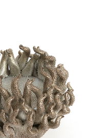 Nahaufnahme eines kunstvoll gestalteten Teelichthalters mit tentakelartigen Strukturen in metallischer Optik.