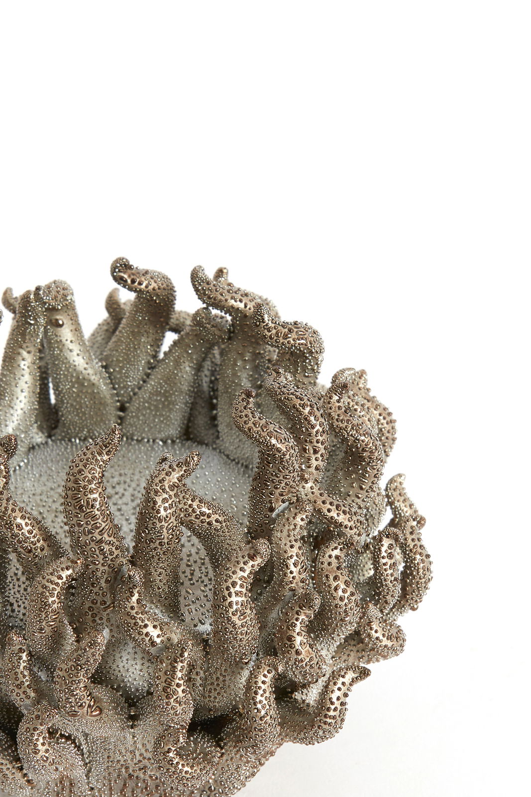 Nahaufnahme eines kunstvoll gestalteten Teelichthalters mit tentakelartigen Strukturen in metallischer Optik.