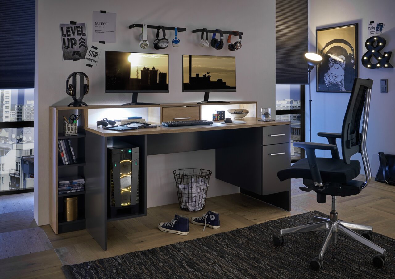 Een gamingtafel met twee beeldschermen, een toetsenbord en een muis, omringd door koptelefoons en decoraties, gezien vanuit een gezellige gamekamer.