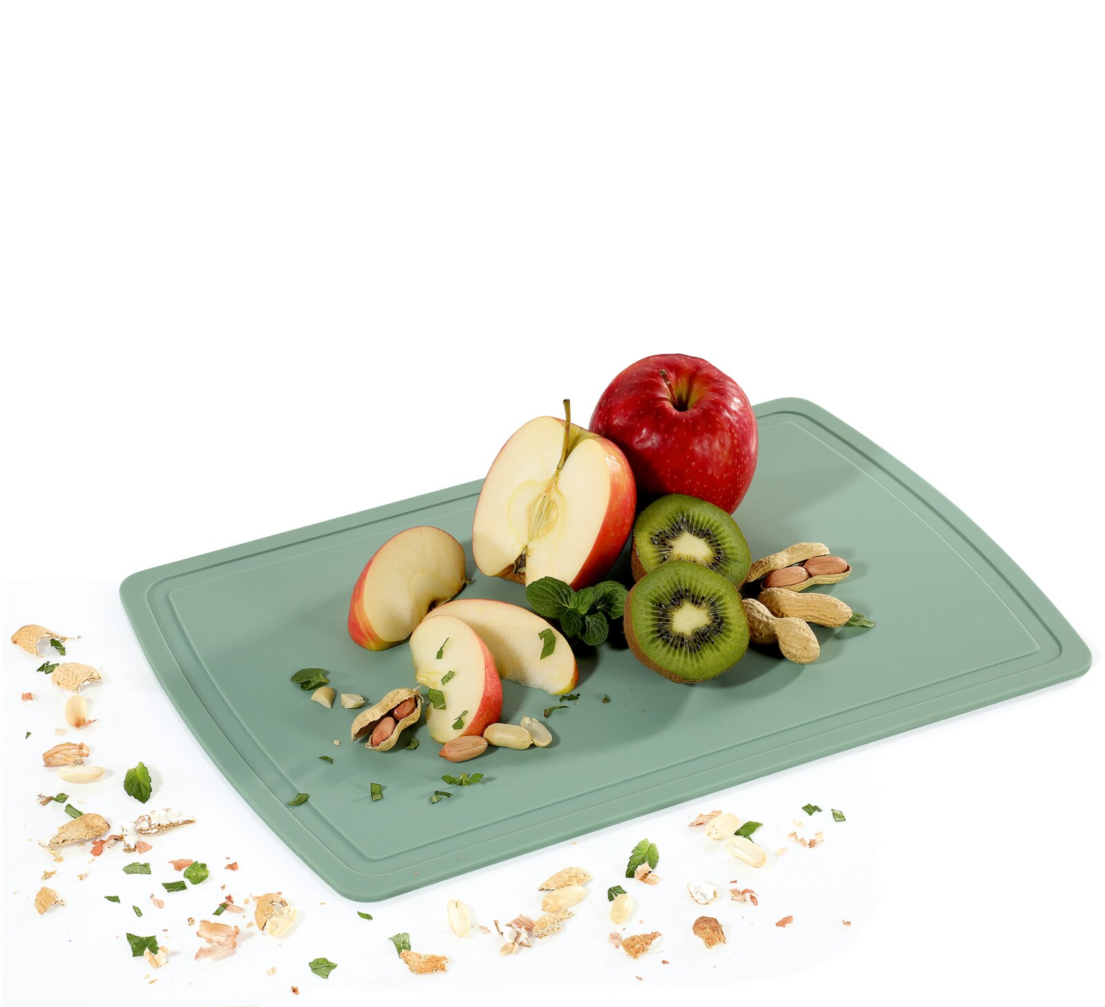 Salbeigrünes Schneidebrett mit Äpfeln, Kiwis, Erdnüssen und Minze aus schräger Vogelperspektive