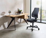 Moderner Schreibtisch aus Holz mit schwarzen Metallbeinen, dekoriert mit einer Lampe, Pflanzen und Büchern, seitliche Perspektive.