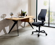 Moderner Schreibtisch aus Holz mit schwarzen Metallbeinen, dekoriert mit einer Lampe, Pflanzen und Büchern, seitliche Perspektive.