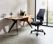 Moderner Schreibtisch aus Holz mit schwarzen Metallbeinen, dekoriert mit einer Lampe, Pflanzen und Büchern, seitliche Perspektive.