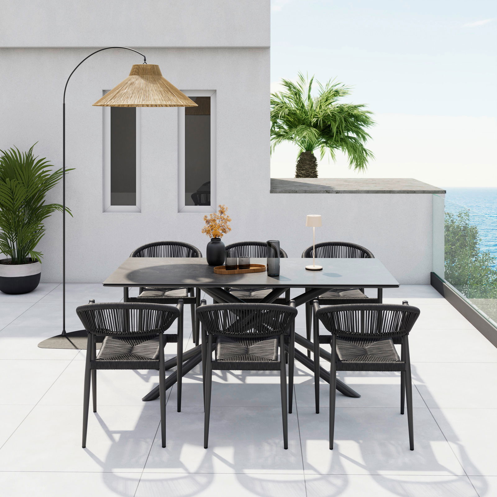 Moderner Stapelsessel auf einer Terrasse mit Meerblick, umgeben von einem stilvollen Esstisch-Set und Pflanzen, aus der Vogelperspektive fotografiert.