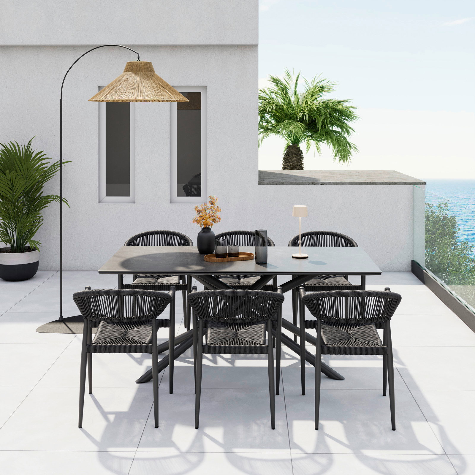 Moderner Stapelsessel auf einer Terrasse mit Meerblick, umgeben von einem stilvollen Esstisch-Set und Pflanzen, aus der Vogelperspektive fotografiert.