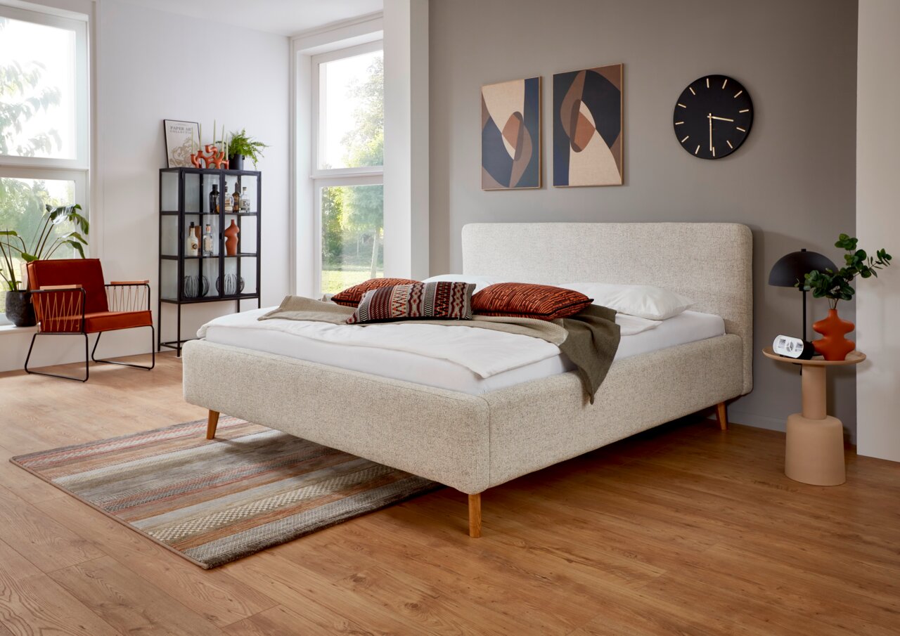 Modernes Polsterbettgestell in einem stilvoll eingerichteten Schlafzimmer, seitliche Perspektive.