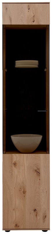 Frontale Ansicht der Valnatura Vitrine LAVIA mit Holzelementen und Glastür, gefüllt mit weißen Tellern und einer Schale.