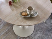 Runder Beistelltisch mit heller Steinoptik-Tischplatte und weißem Mittelfuß, fotografiert in leichter Draufsicht; darauf ein Tablett mit Tasse, Löffel und zwei Keksen.