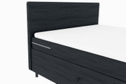 Boxspringbett in dunklem Stoff mit weißer Matratze, seitliche Perspektive