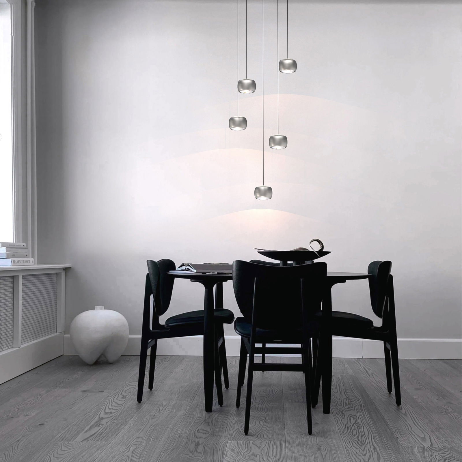 Moderne LED-Pendelleuchte in einem Esszimmer, aus der Seitenperspektive fotografiert, mit fünf hängenden Leuchten über einem Tisch.