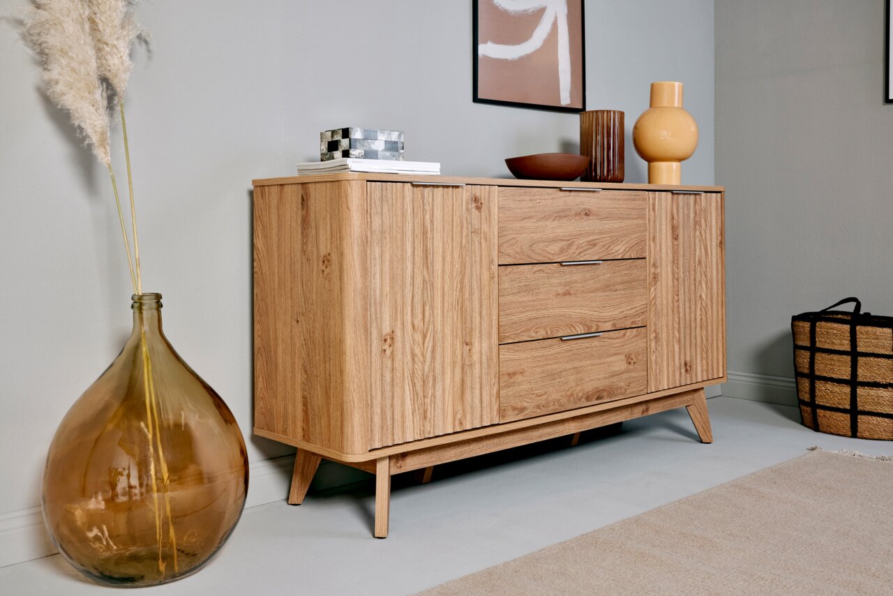 Jahnke Sideboard WAVE Holz-Sideboard mit drei Schubladen und zwei Türen, seitliche Perspektive, dekoriert mit Vasen und Kunstobjekten.
