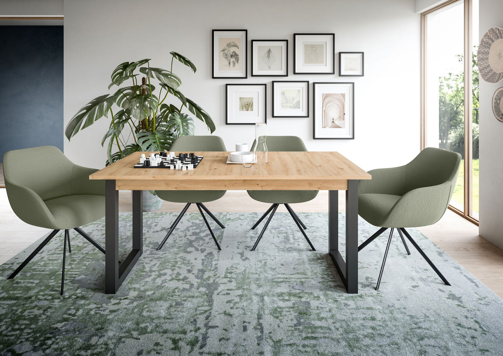 Moderner Esstisch mit Holzplatte und schwarzen Metallbeinen, umgeben von vier grünen Stühlen in einem stilvoll eingerichteten Raum mit Pflanzen und Wandbildern, aus frontaler Perspektive.