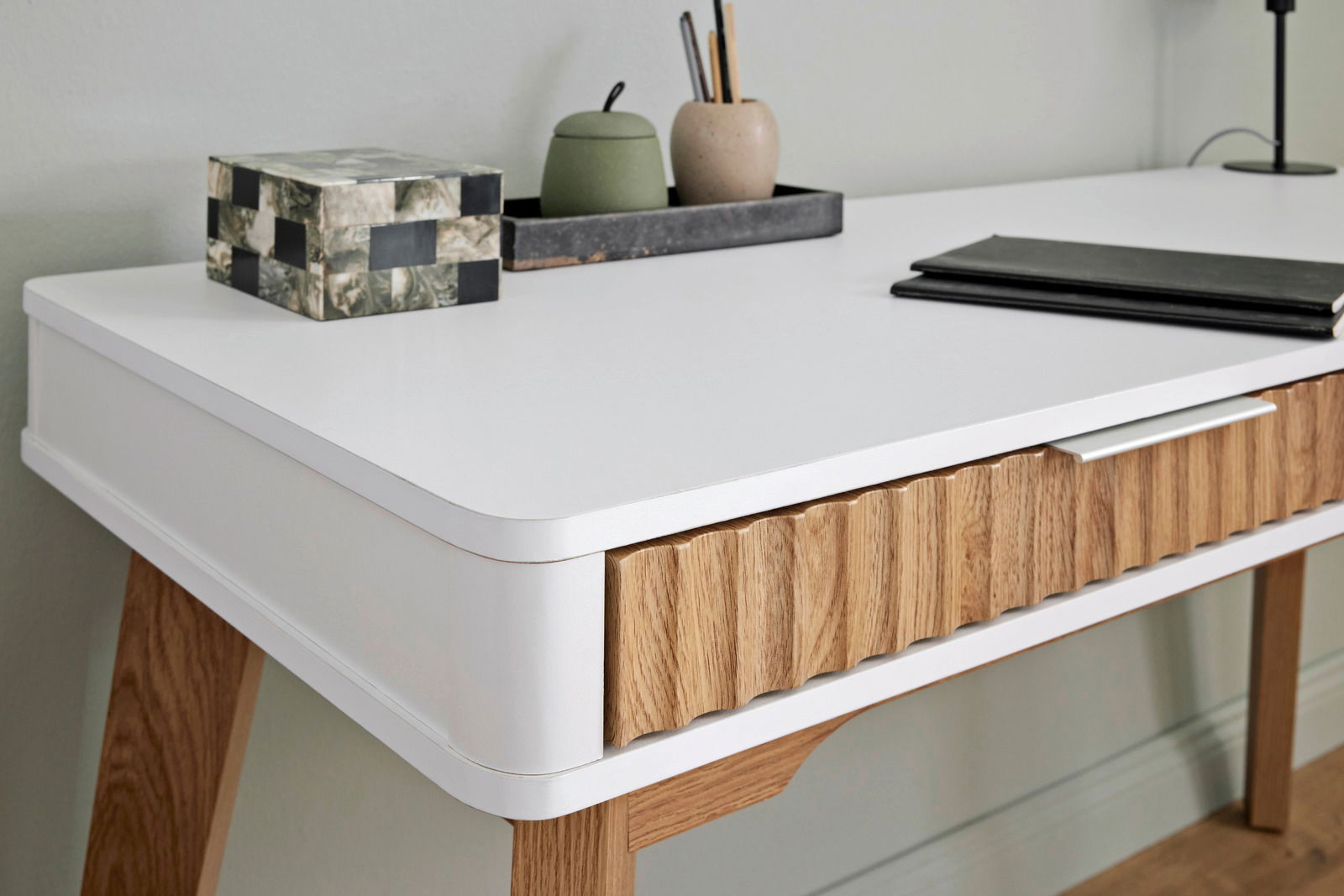 Moderner Schreibtisch mit weißer Oberfläche und Holzdetails, seitliche Perspektive