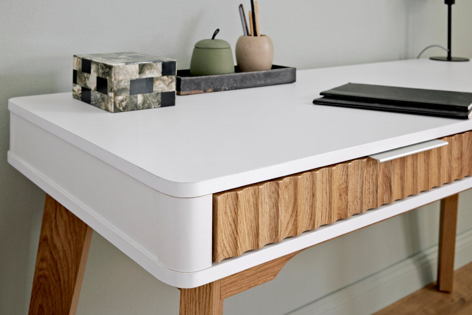 Moderner Schreibtisch mit weißer Oberfläche und Holzdetails, seitliche Perspektive