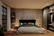 Modernes Schlafzimmer mit grün gepolstertem Bett, grauer Bettwäsche, Betonwand, Pendelleuchten, Nachttischen, Regal und offenem Kleiderschrank; frontale Perspektive auf das Bett.