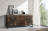 Rustikales Sideboard aus Holz mit Fischgrätenmuster, frontal fotografiert, dekoriert mit zwei gerahmten Bildern und Vasen, vor einer weißen Backsteinwand.