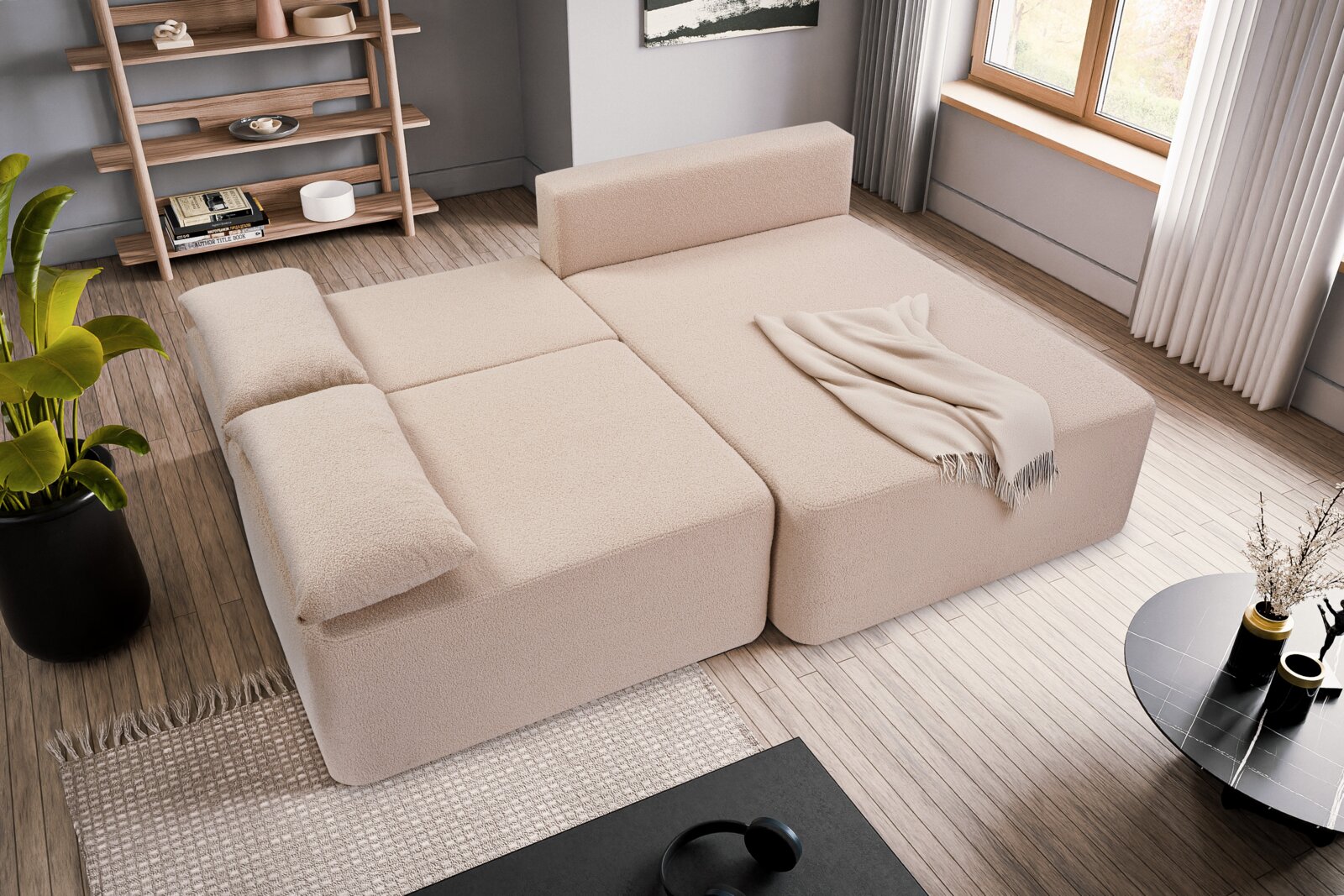 Beige Schlafsofa in L-Form von oben betrachtet, mit Kissen und Decke, in einem modernen Wohnzimmer mit Holzfußboden und großen Fenstern.