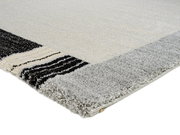 Nahaufnahme eines Webteppichs Castle Flora in Grau- und Schwarztönen, perspektivisch von der Seite fotografiert.