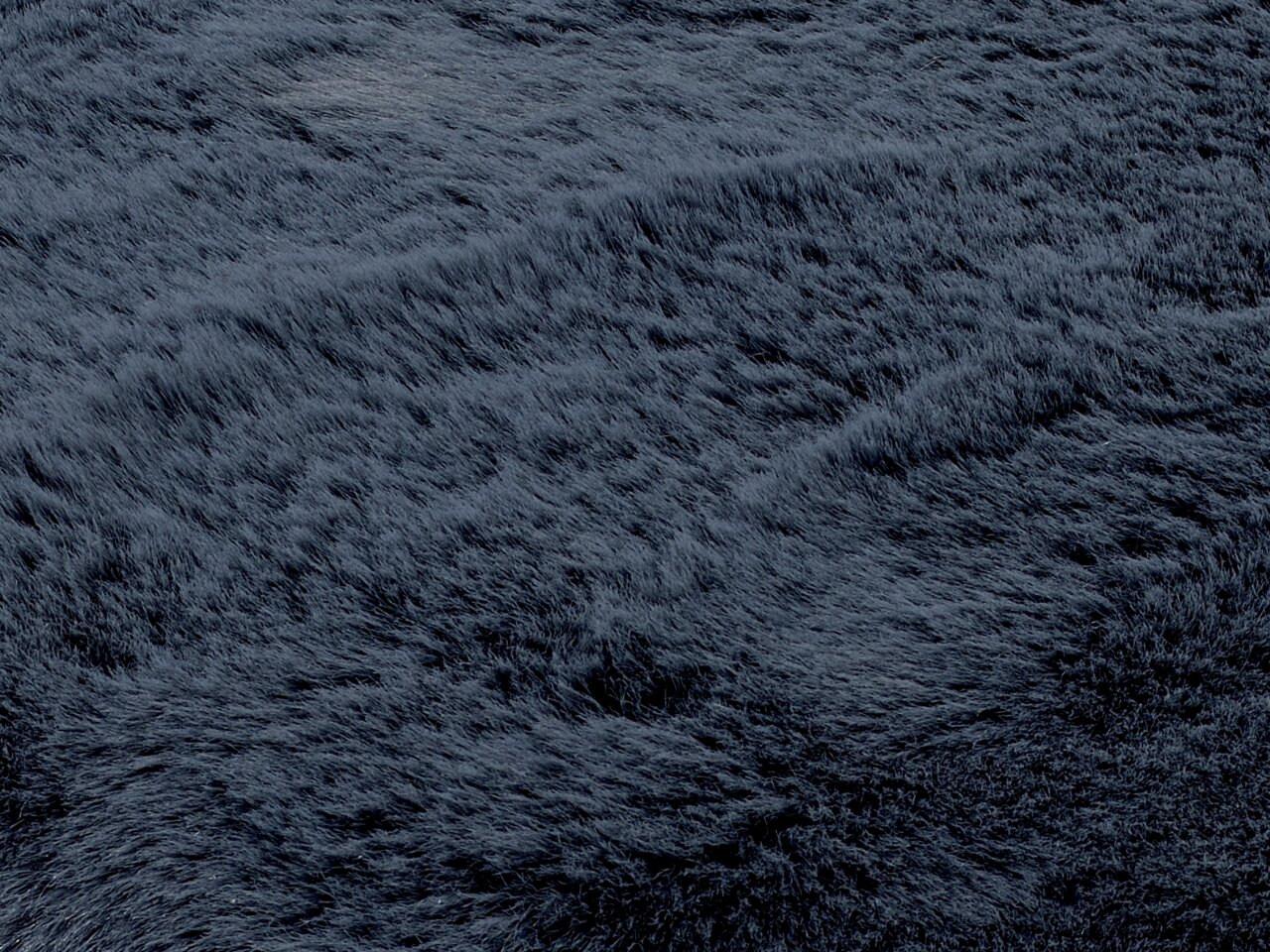 Nahaufnahme eines dunkelgrauen Fellteppichs mit weicher, flauschiger Textur.
