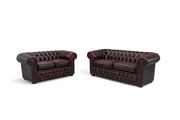 Zwei Chesterfield Sofas in dunklem Leder, frontal fotografiert, mit charakteristischer Knopfheftung und abgerundeten Armlehnen.