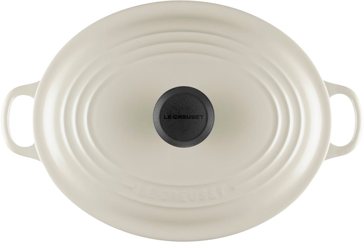 Ovaler Le Creuset Gusseisen-Bräter mit Deckel in Cremeweiß, mit seitlichen Griffen und schwarzem Deckelknopf, Draufsicht von oben