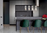 Moderne Küche mit drei eleganten Hängeleuchten über einer Theke, grüne Samtstühle und graue Schränke, seitliche Perspektive.