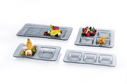 Verschiedene rechteckige Servierplatten und Schalen aus Glas mit strukturiertem Design, von oben fotografiert, dekoriert mit Obst und Desserts.