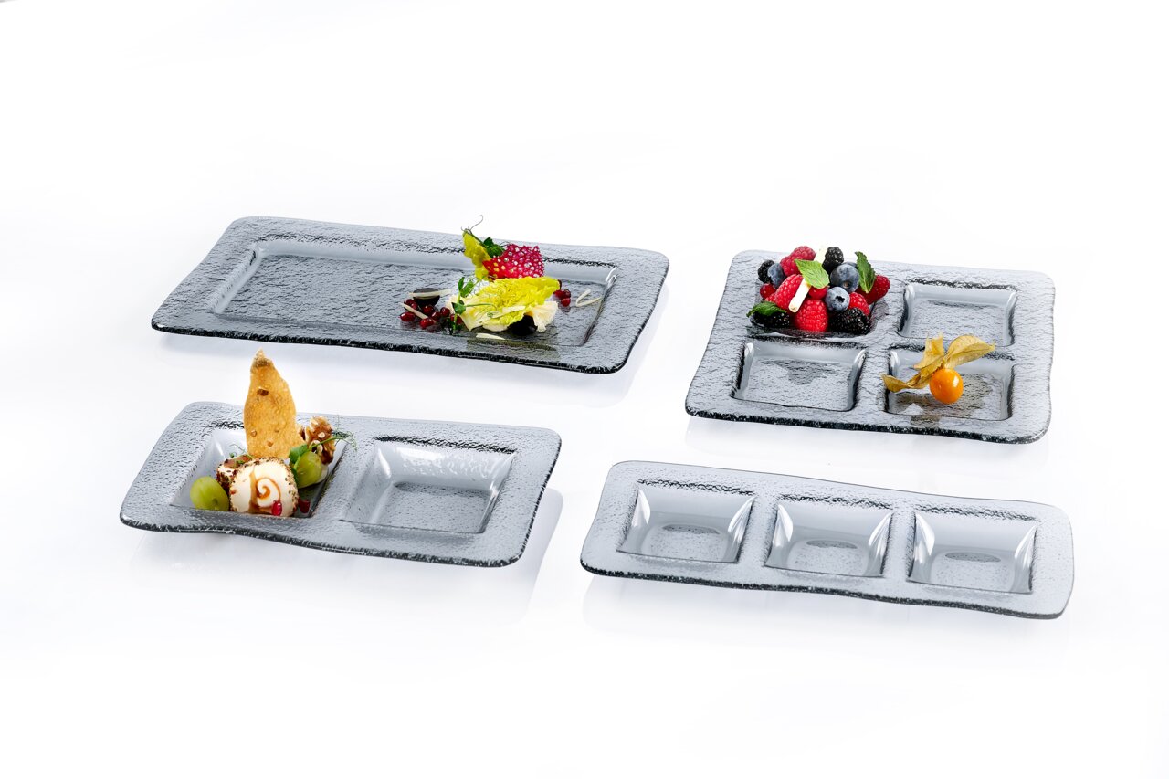Ritzenhoff & Breker Servierschale NOX Verschiedene rechteckige Servierplatten und Schalen aus Glas mit strukturiertem Design, von oben fotografiert, dekoriert mit Obst und Desserts.