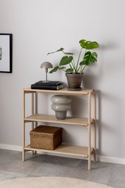 Holzregal mit drei Ebenen, dekoriert mit einer Pflanze, einer Lampe, Büchern und einem Korb, seitliche Perspektive