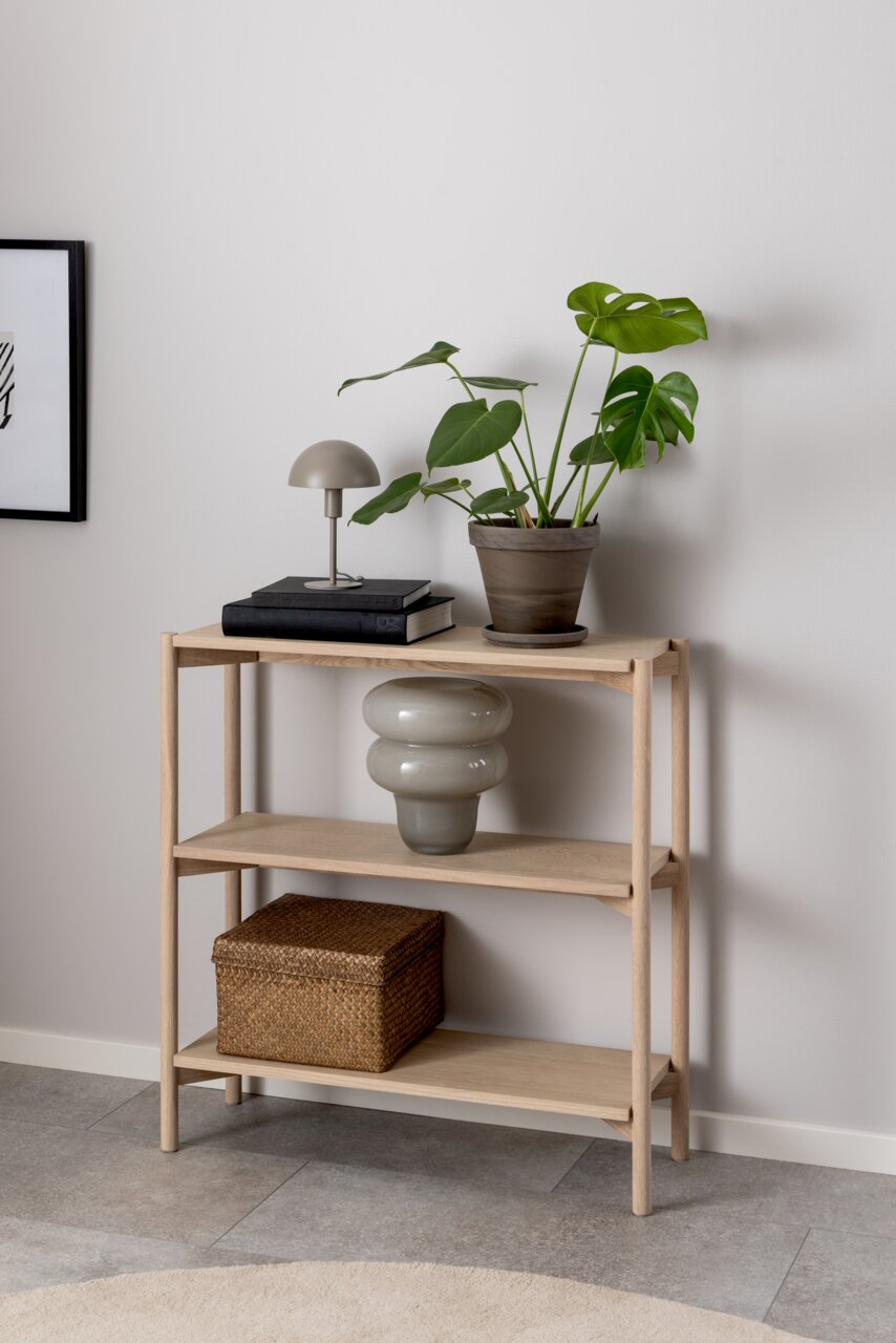 Holzregal mit drei Ebenen, dekoriert mit einer Pflanze, einer Lampe, Büchern und einem Korb, seitliche Perspektive