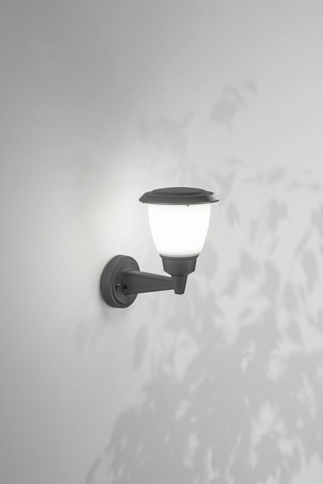 Fabas Luce Außenwandleuchte THIAGO Außenwandleuchte mit klassischem Design, seitliche Perspektive, montiert an einer weißen Wand, beleuchtet mit weichem Licht.