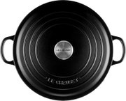 Bovenaanzicht van een ronde zwarte Le Creuset-braadpan met deksel, twee handgrepen en een zilverkleurige knop