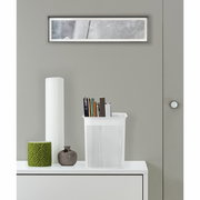 Weiße, schmale Aufbewahrungsbox mit perforiertem Design, gefüllt mit Büchern, auf einem weißen Möbelstück stehend, aus frontaler Perspektive.