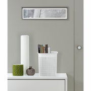 Weiße, schmale Aufbewahrungsbox mit perforiertem Design, gefüllt mit Büchern, auf einem weißen Möbelstück stehend, aus frontaler Perspektive.