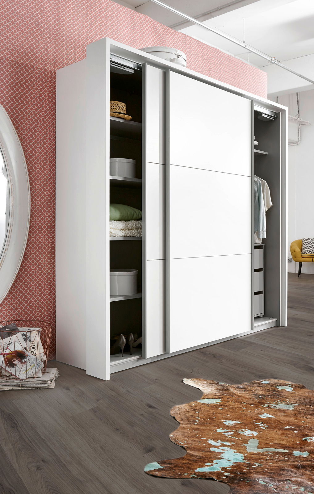 Moderner weißer Schwebetürenschrank mit zwei offenen Türen, die Einblick in die Regale und Kleiderstangen geben, seitliche Perspektive.