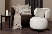 Zwei moderne Sessel mit stilvollen Zierkissen in einem eleganten Wohnzimmer-Setup, seitliche Perspektive.