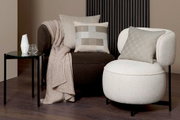 Zwei moderne Sessel mit stilvollen Zierkissen in einem eleganten Wohnzimmer-Setup, seitliche Perspektive.