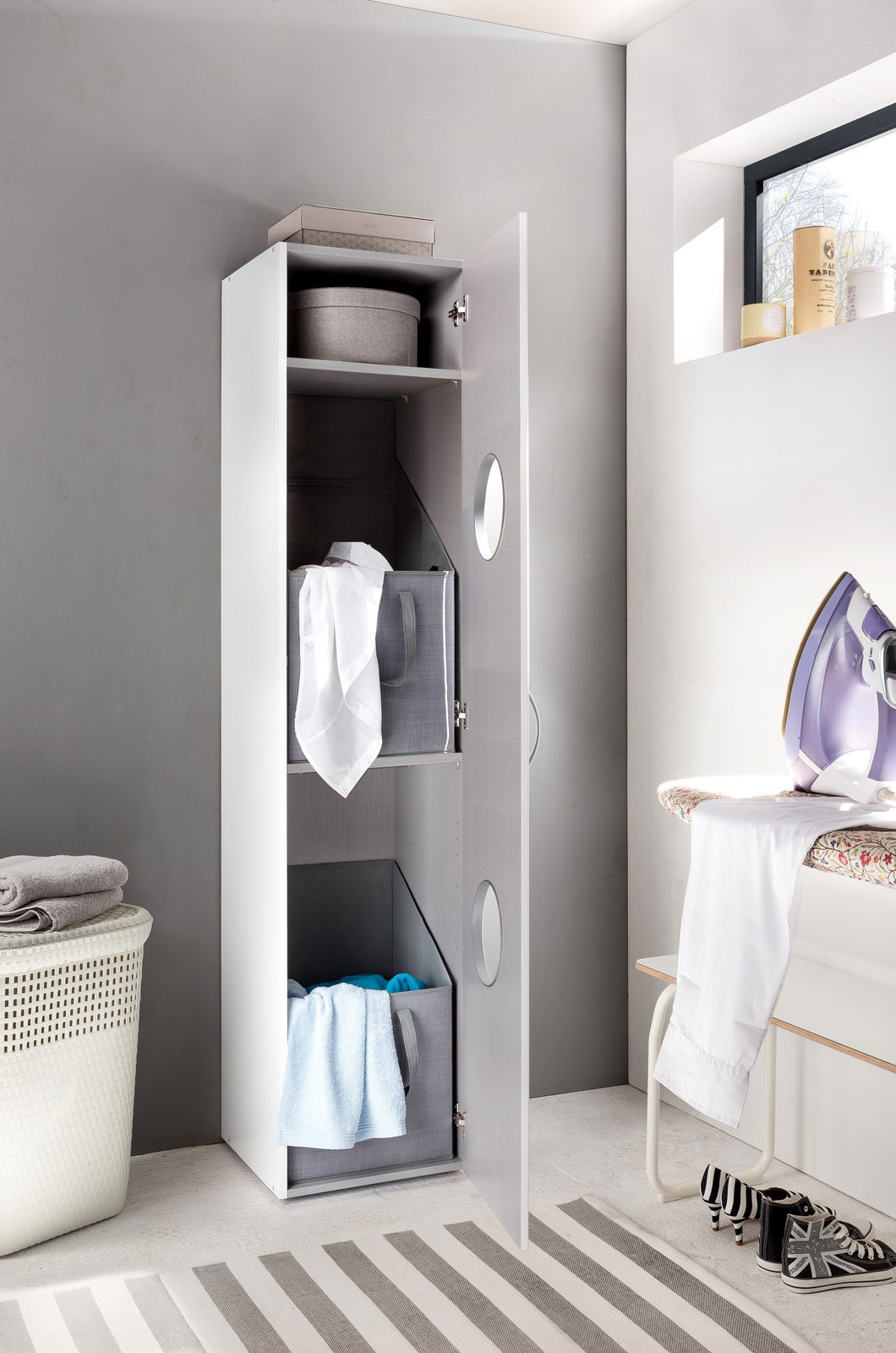 Moderner Wäscheschrank mit geöffneter Tür, gefüllt mit Wäschekörben und Handtüchern, aus seitlicher Perspektive fotografiert.