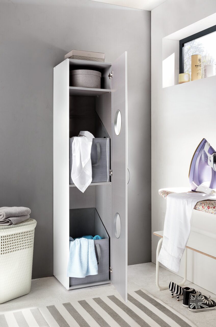 Moderner Wäscheschrank mit geöffneter Tür, gefüllt mit Wäschekörben und Handtüchern, aus seitlicher Perspektive fotografiert.