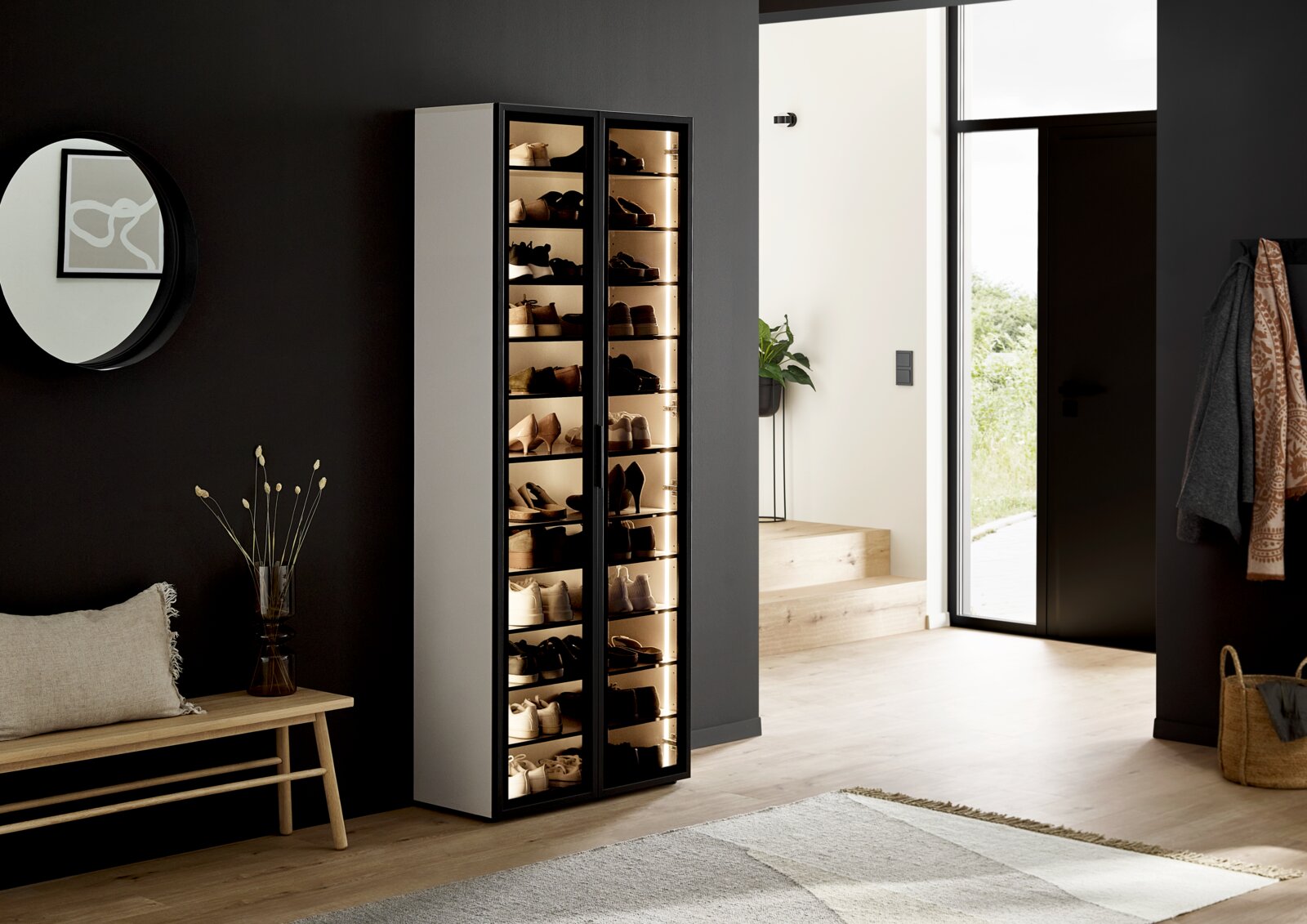 Voleo XL-schoenenkast-vitrine KIARA XL-schoenenkast met glazen deuren, gevuld met schoenen, in een moderne hal, zijaanzicht